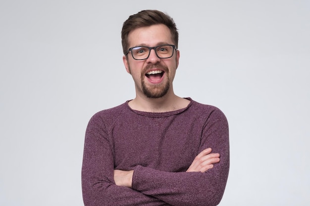 Souriant jeune homme avec barbe et lunettes regardant la caméra