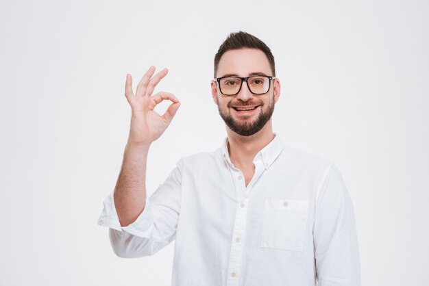 Souriant jeune homme barbu posant avec un geste correct