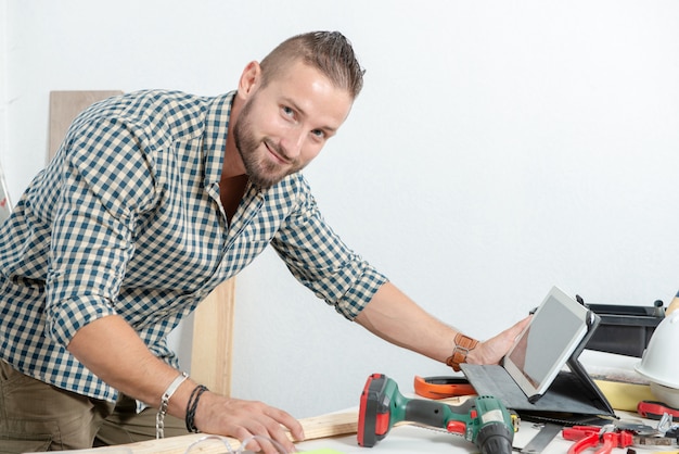 Souriant jeune homme bricolage à la maison avec tablette