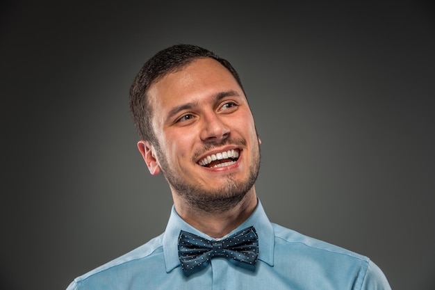 Souriant jeune homme en chemise bleue et cravate papillon