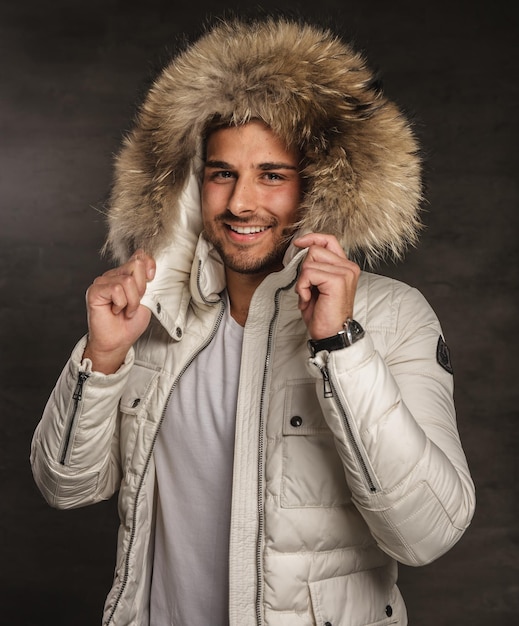 Souriant jeune homme en manteau chaud d'hiver avec capuche en fourrure.