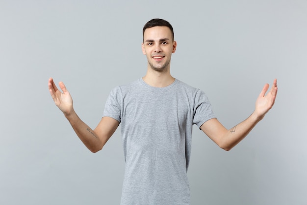 Souriant jeune homme séduisant dans des vêtements décontractés faisant des gestes démontrant la taille avec un espace de travail horizontal