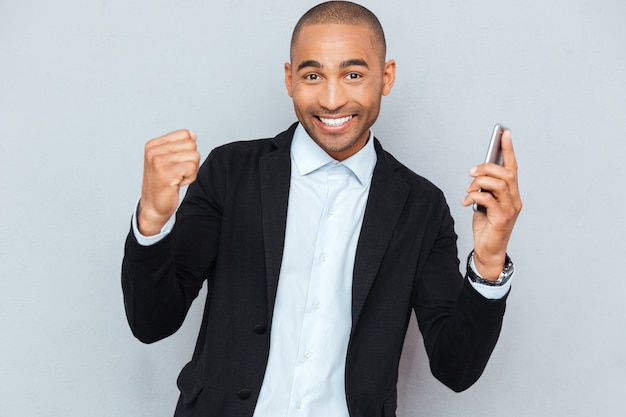 Photo souriant jeune homme avec téléphone intelligent isolé sur fond gris