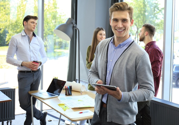 Souriant jeune homme utilisant une tablette numérique au bureau.