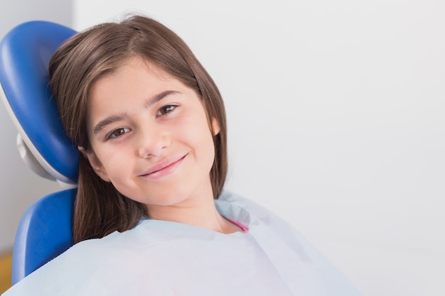 Souriant jeune patient assis dans une chaise de dentistes