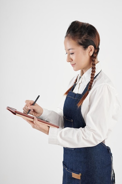 Souriant jeune propriétaire de coffeeshop signant le document de la tablette tactile