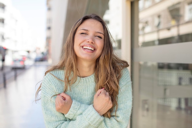 souriant joyeusement et célébrant avec les poings serrés et les bras croisés se sentant heureux et positif