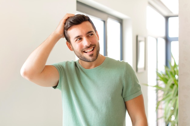 souriant joyeusement et avec désinvolture, prenant la main à la tête avec un regard positif, heureux et confiant