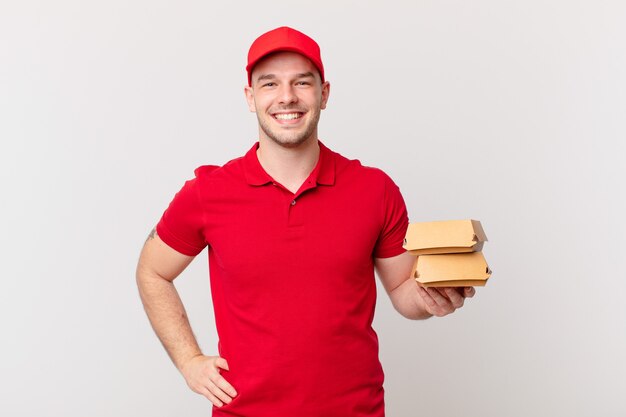 souriant joyeusement avec une main sur la hanche et une attitude confiante, positive, fière et amicale