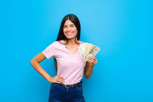 souriant joyeusement avec une main sur la hanche et une attitude confiante, positive, fière et amicale