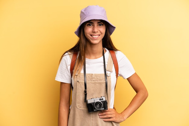 souriant joyeusement avec une main sur la hanche et confiant