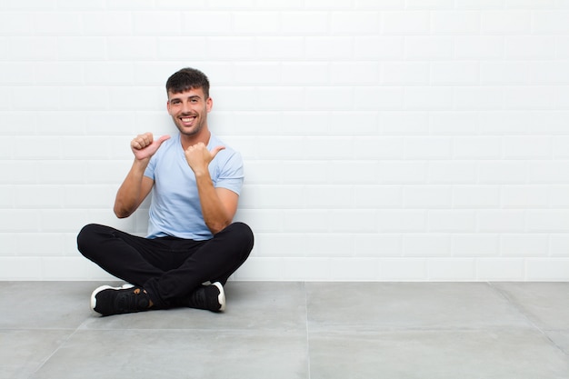 souriant joyeusement et nonchalamment pointant pour copier l'espace sur le côté, se sentant heureux et satisfait