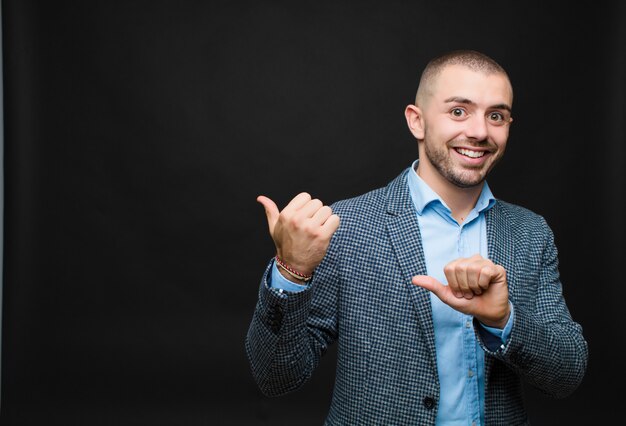 souriant joyeusement et nonchalamment pointant pour copier l'espace sur le côté, se sentant heureux et satisfait