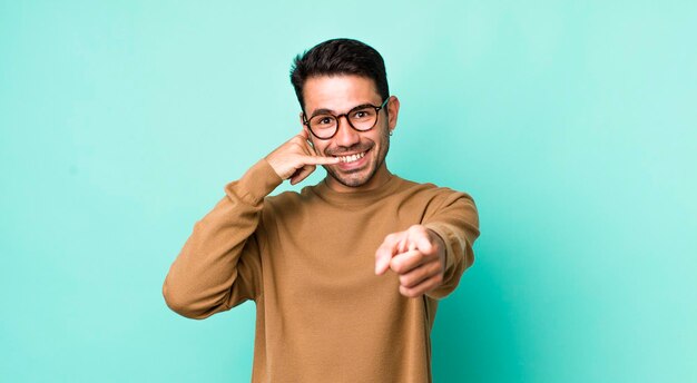 Souriant joyeusement et pointant vers la caméra tout en passant un appel, vous faites plus tard un geste en parlant au téléphone