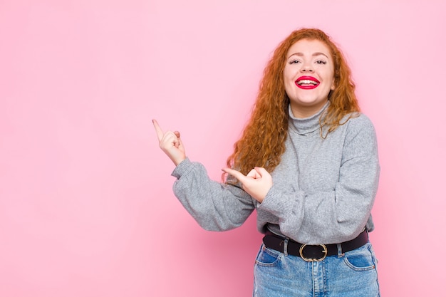 souriant joyeusement et pointant vers le côté et vers le haut avec les deux mains montrant l'objet dans l'espace de copie