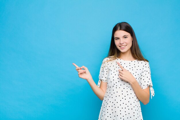 souriant joyeusement et pointant vers le côté et vers le haut avec les deux mains montrant l'objet dans l'espace de copie