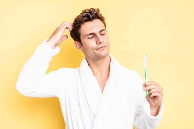 Souriant joyeusement et rêvant ou doutant, regardant de côté. concept de brosse à dents