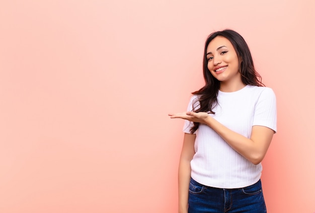 souriant joyeusement, se sentant heureux et montrant un concept dans l'espace de copie avec la paume de la main