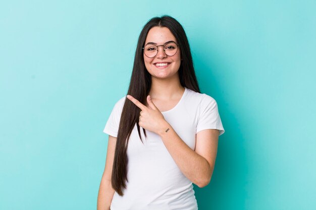 souriant joyeusement se sentant heureux et pointant vers le côté et vers le haut montrant l'objet dans l'espace de copie