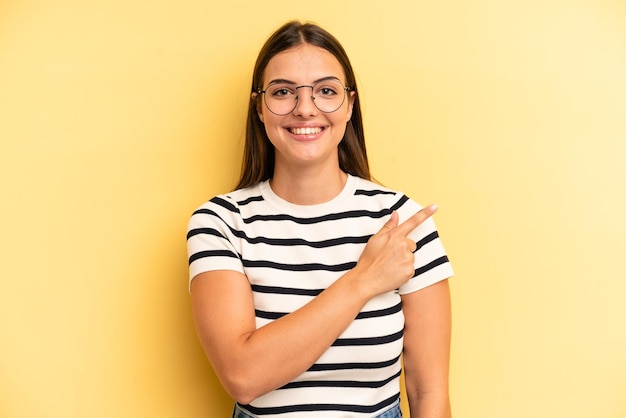 souriant joyeusement se sentant heureux et pointant vers le côté et vers le haut montrant l'objet dans l'espace de copie