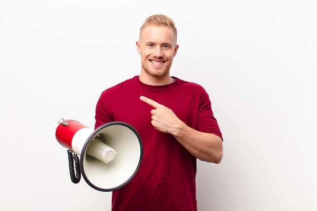 souriant joyeusement, se sentant heureux et pointant vers le côté et vers le haut, montrant l'objet