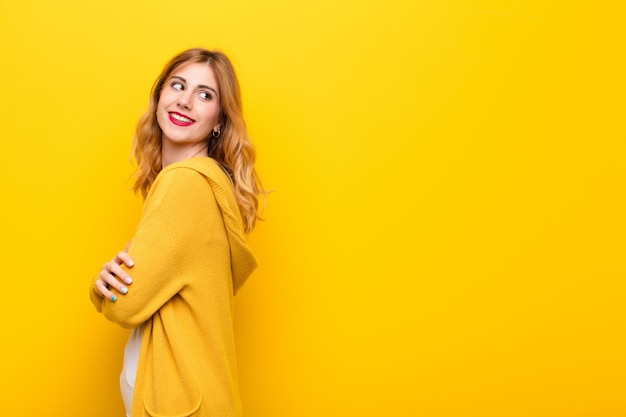 souriant joyeusement, se sentant heureux, satisfait et détendu, les bras croisés et regardant de côté