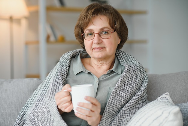 Souriant mature aîné 65 ans femme assise relaxante avec une tasse de thé café