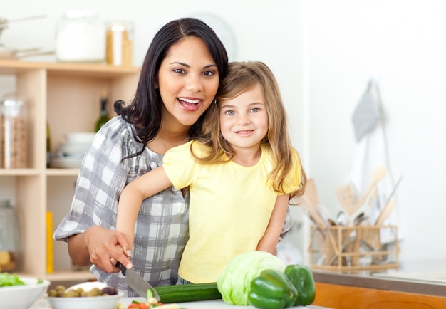 Souriant mère et fille coupant les légumes ensemble