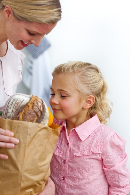 Souriant mère et sa fille déballage sac d&#39;épicerie