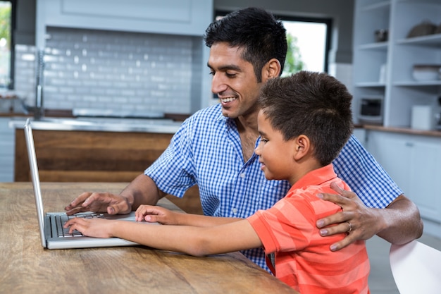 Souriant père utilisant un ordinateur portable avec son fils