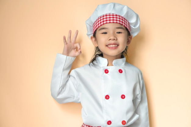 Souriant petit chef asiatique avec chapeau isolé sur fond orange