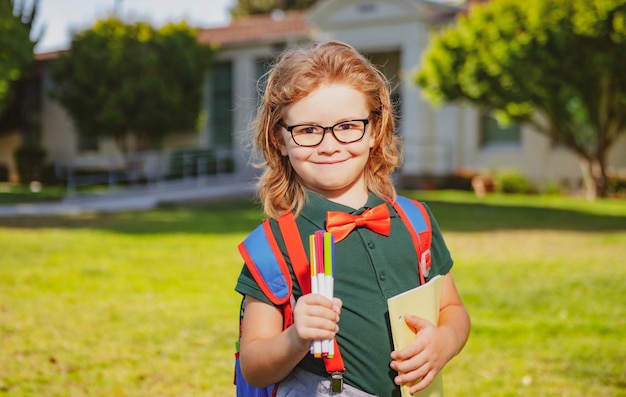 Souriant petit écolier avec sac à dos livre portrait d'élève écolier heureux en plein air