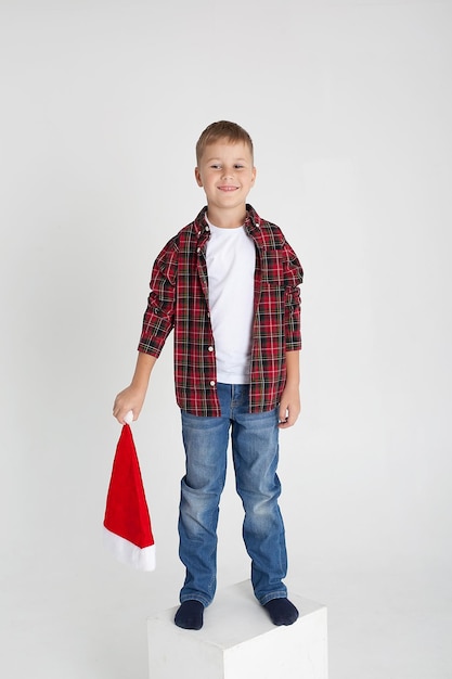 Souriant petit garçon au chapeau du père Noël avec boîte-cadeau isolé sur blanc