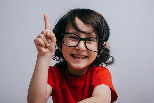 Souriant petit garçon levant la main