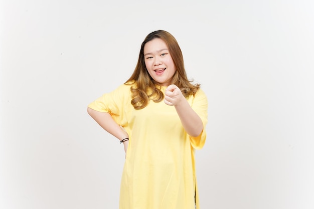 Souriant et pointant vers vous de belle femme asiatique portant un t-shirt jaune isolé sur blanc