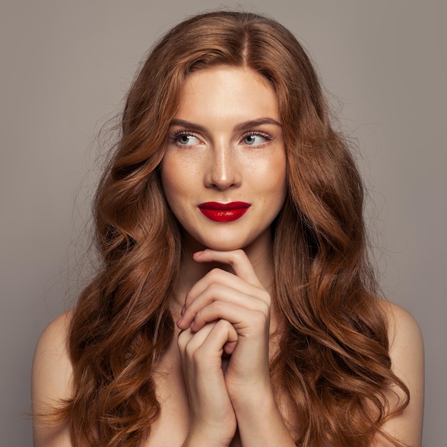 Souriant portrait de femme aux cheveux rouge. Jolie fille rousse aux cheveux bouclés