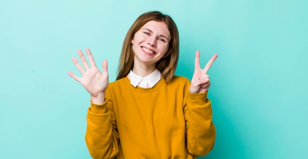 Souriant et regardant amicalement montrant le numéro sept ou sept avec la main en avant comptant à rebours