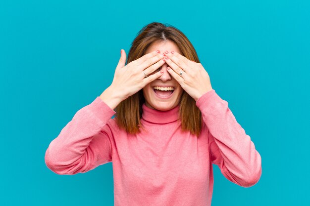 souriant et se sentant heureux, couvrant les yeux des deux mains et attendant une surprise incroyable