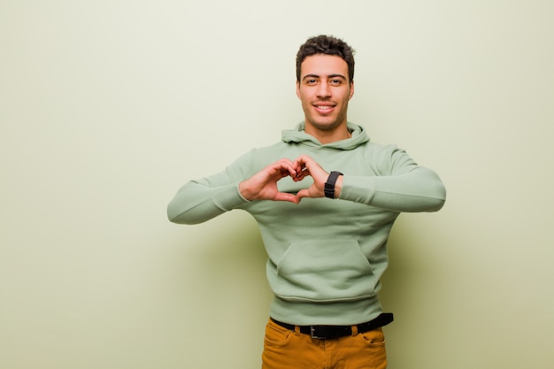 souriant et se sentant heureux, mignon, romantique et amoureux, en forme de cœur avec les deux mains