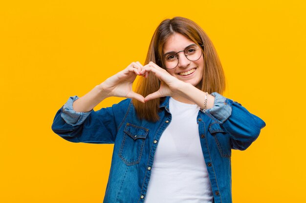 souriant et se sentant heureux, mignon, romantique et amoureux, en forme de cœur avec les deux mains