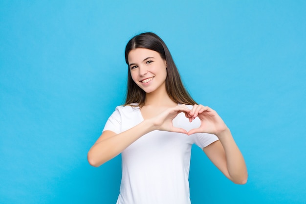 souriant et se sentant heureux, mignon, romantique et amoureux, en forme de cœur avec les deux mains