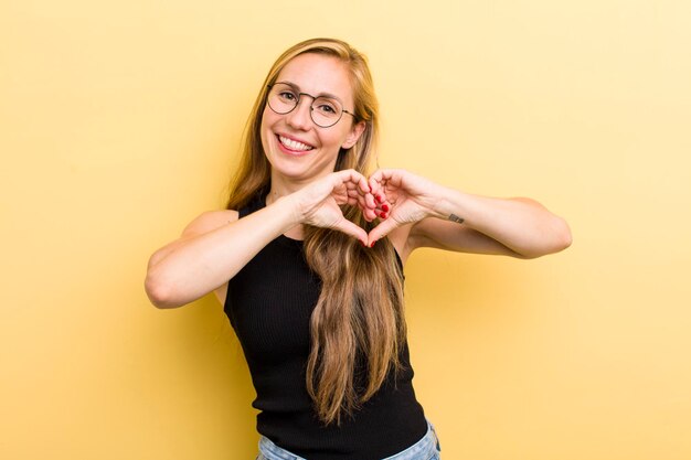 souriant et se sentir heureux mignon romantique et amoureux en forme de coeur avec les deux mains