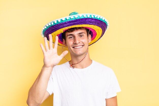 Souriant et semblant amical, montrant le numéro cinq ou cinquième avec la main en avant, compte à rebours. concept de chapeau mexicain