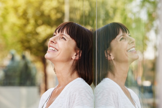 Souriant sympathique femme appuyé contre la réflexion dans la construction