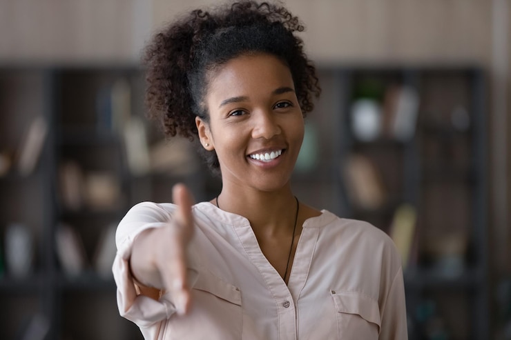 Photo souriant sympathique générique millénaire authentique positive d'ethnie africaine femme tendant la main pour serrer la main geste de salut se sentant satisfait d'accueillir un nouveau client ou de se familiariser à l'intérieur