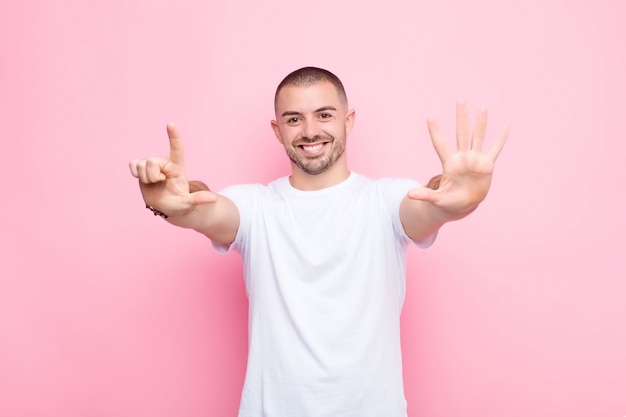 souriant et sympathique, montrant le numéro sept ou septième avec la main en avant, le compte à rebours