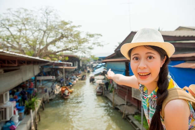 souriant voyageur heureux montrant un geste de pointage vendeurs de rivière colporteur magasin joyeux gros plan debout sur le marché flottant de Damnoen Saduak en vacances de Thaïlande, en Asie.