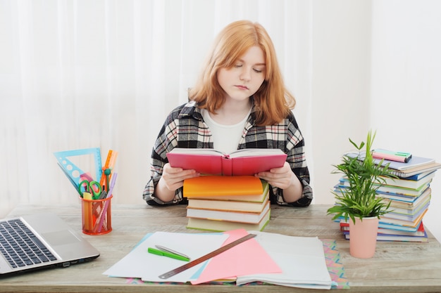 Souriante adolescente étudiante faisant ses devoirs à la maison, l'éducation et le concept de l'école