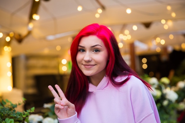 Souriante belle adolescente rousse le soir dans une rue éclairée de la ville.