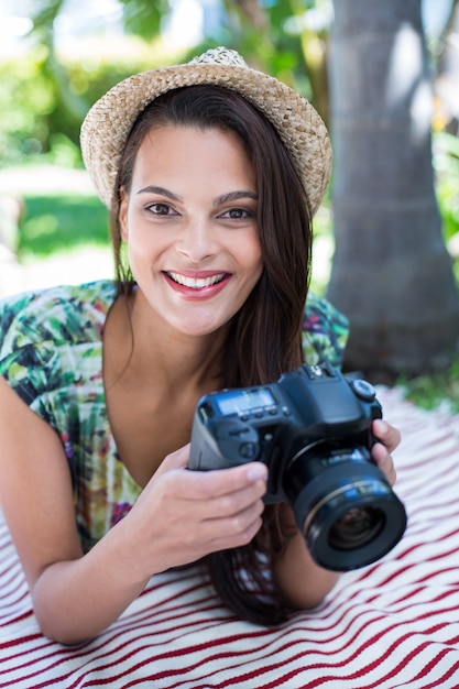 Souriante belle brune allongée sur la couverture et prendre des photos